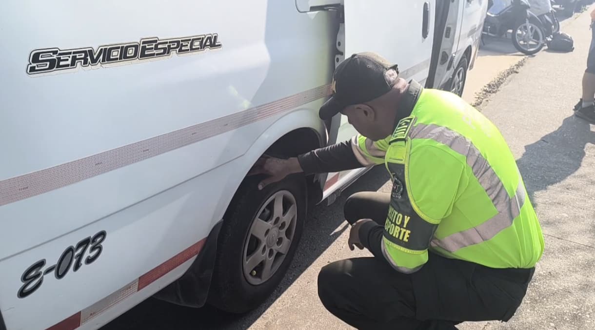 Un uniformado de la policía revisando el estado de las llantas de un carro de transporte escolar. Foto suministrada.