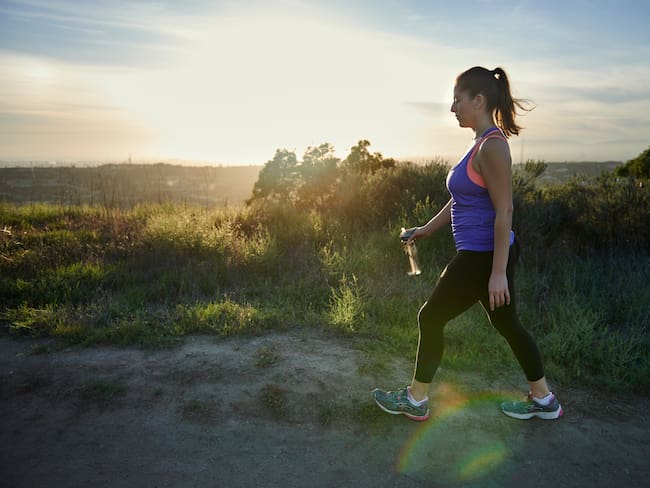 Mujer haciendo ejercicio caminando sobre una montaña (Getty Images)