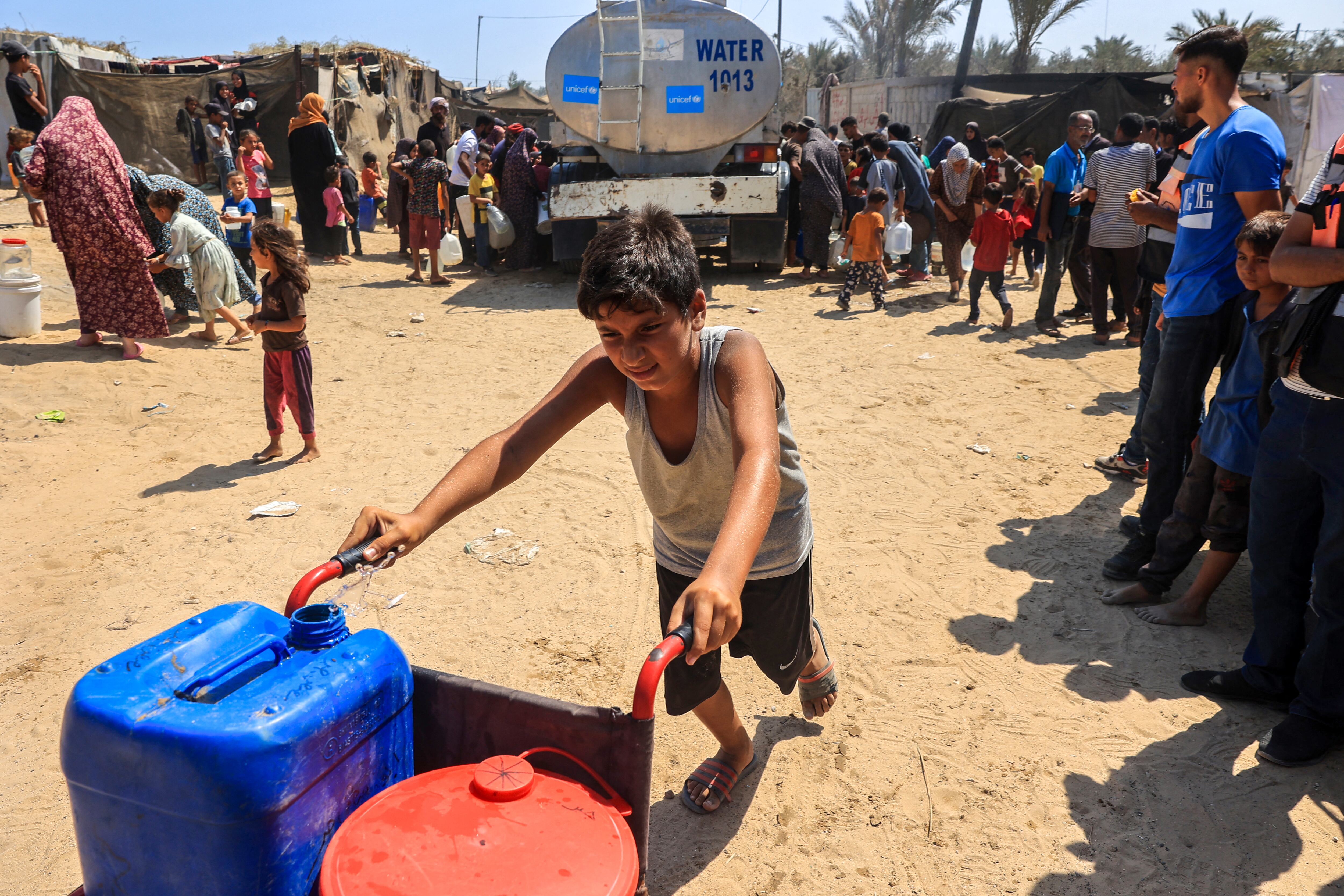 Palestinians collect water from a UNICEF tanker in Deir el-Balah in the central Gaza Strip on July 9, 2024, amid the ongoing conflict between Israel and the Palestinian Hamas militant group. (Photo by Eyad BABA / AFP) (Photo by EYAD BABA/AFP via Getty Images)