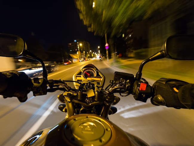Motociclista conduciendo de noche a gran velocidad (Getty Images)