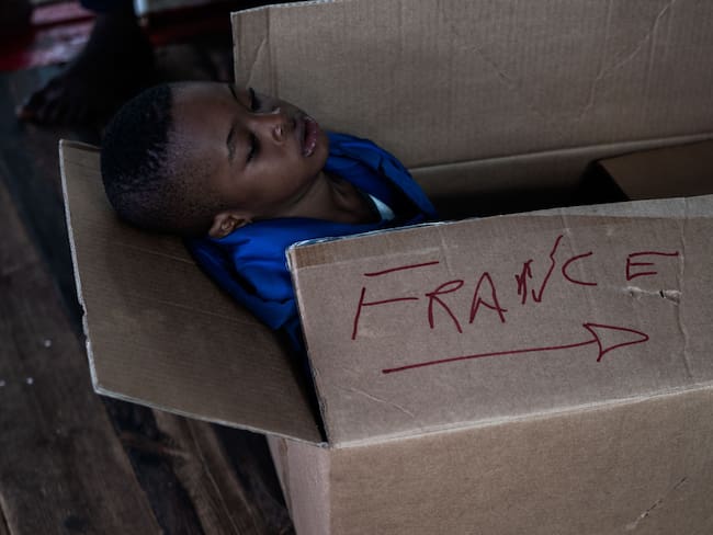 Un niño migrante duerme en una caja con la inscripción de &quot;Francia&quot; tras ser rescatado en el mar mediterraneo. 
(Foto: VINCENZO CIRCOSTA/AFP via Getty Images)