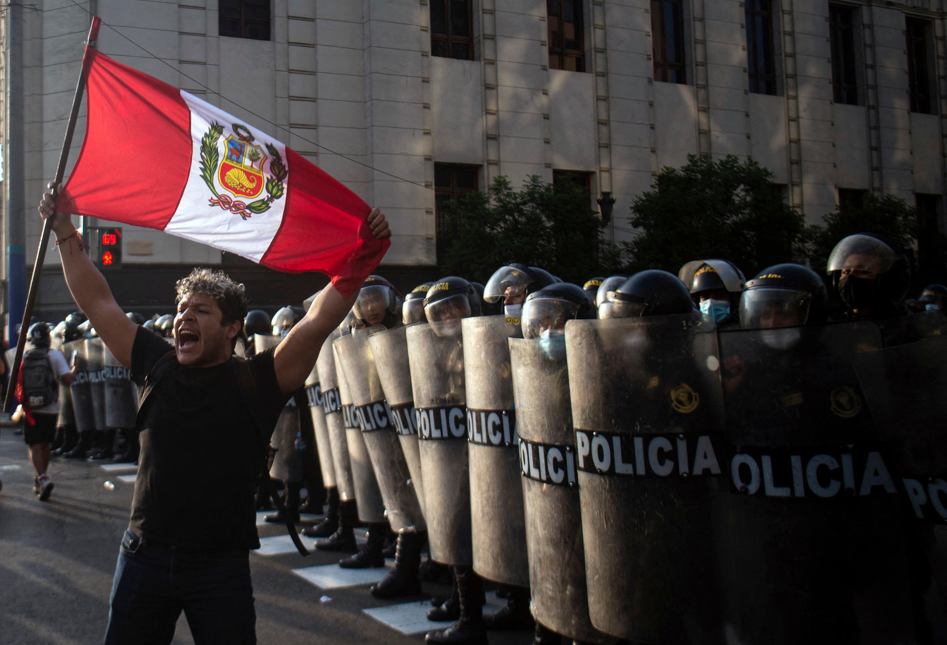 A demonstrator stands in front of riot police members during a protest against the governement of Peru's President Pedro Castillo, in Lima on April 05, 2022 - Peruvian President Pedro Castillo announced the end of a curfew in the capital Lima aimed at containing protests against rising fuel prices following crisis talks with Congress. (Photo by ERNESTO BENAVIDES / AFP) (Photo by ERNESTO BENAVIDES/AFP via Getty Images)