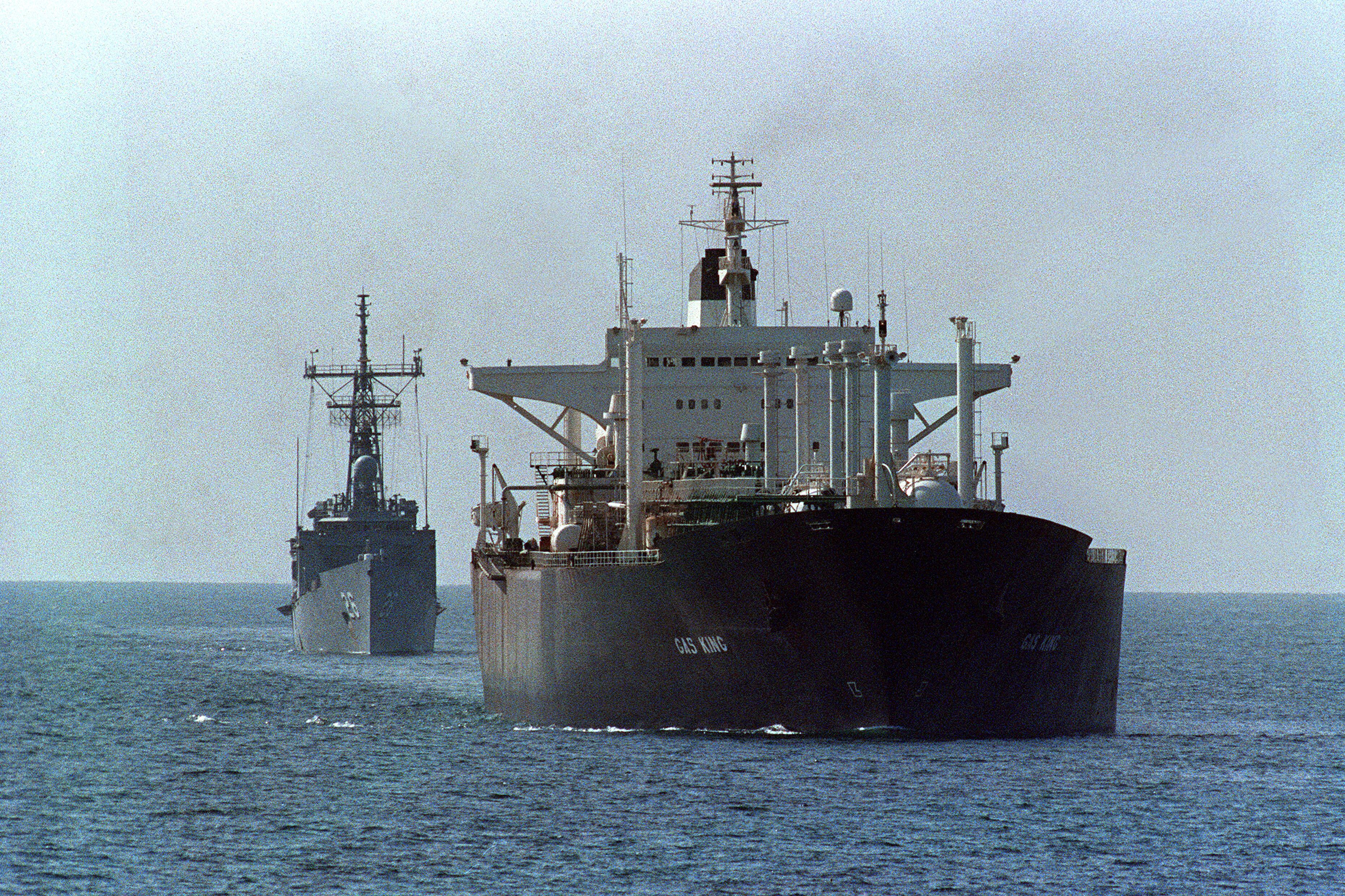 The reflagged tanker Gas King (foreground) loaded with Kuwaiti crude is escorted December 28, 1988 by the U.S. guided missile frigate, USS Gallery towards the Strait of Hormuz, off the Dubai coast.  Two Kuwaiti minesweeping tugs (not pictured here) led the small convoy.  The Tanker War started properly in 1984 when Iraq attacked Iranian tankers and the vital oil terminal at Kharg island. Iran struck back by attacking tankers carrying Iraqi oil from Kuwait and then any tanker of the Gulf states supporting Iraq. The air and small boat attacks did very little to damage the economies of either country and the price of oil was never seriously affected as Iran just moved it's shipping port to Larak Island in the straights of Hormuz.    AFP PHOTO NORBERT SCHILLER (Photo by NORBERT SCHILLER / AFP)