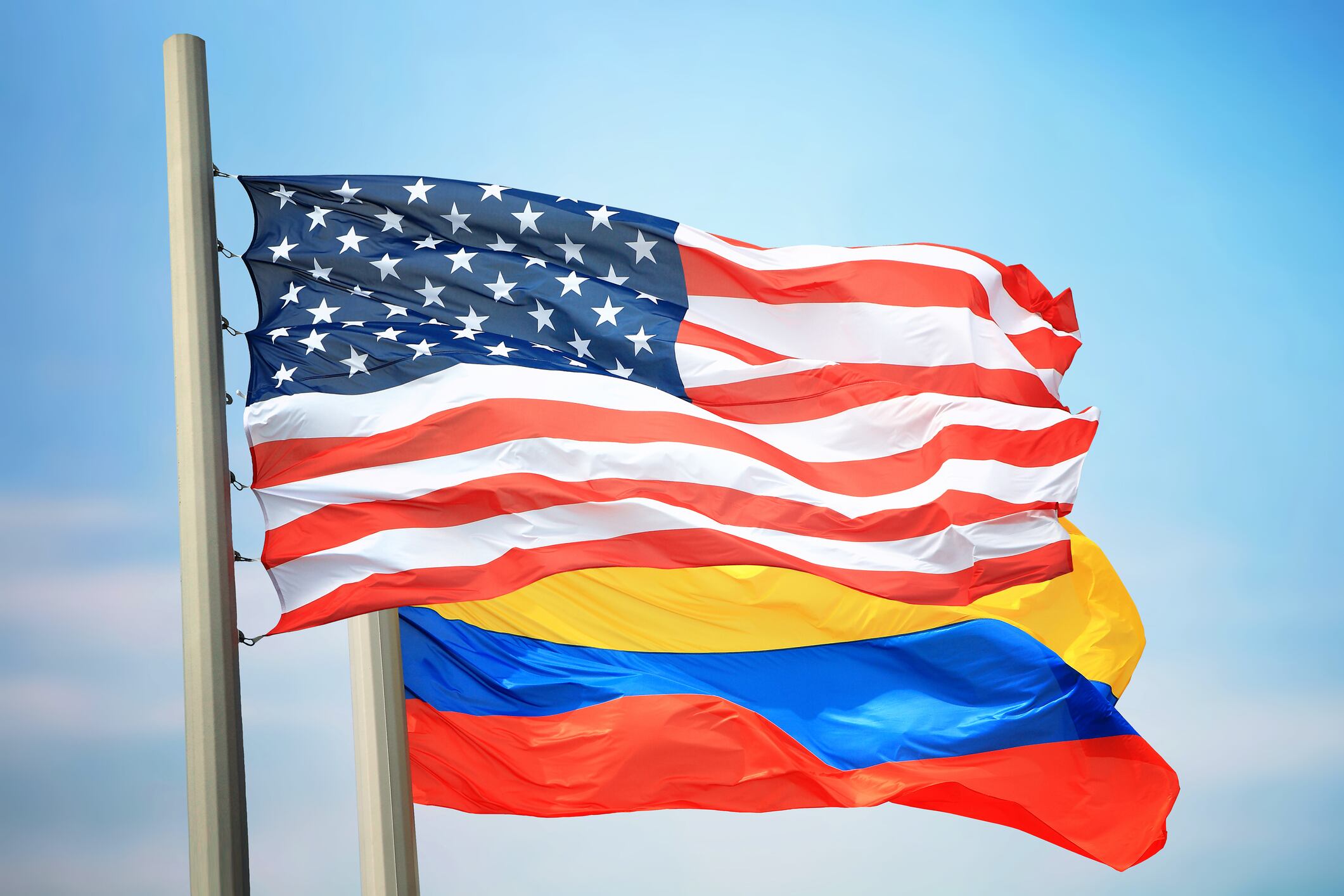 Flags of the USA and Colombia against the background of the blue sky