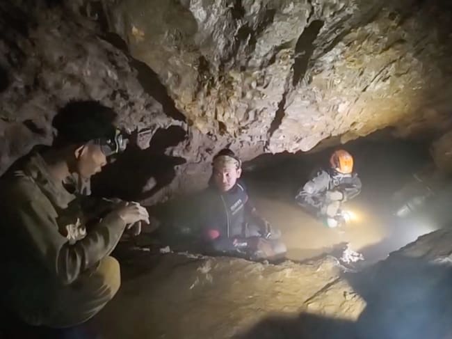 Esta captura de pantalla, tomada de un video facilitado el 29 de mayo de 2026 y proporcionado por Benz Norrased Palasing de Seascout Diving, muestra a un equipo de rescate (C, D) a punto de liberar a uno (I) de los siete hombres atrapados en una cueva semisumergida en la provincia central de Xaysomboun, al noreste de la capital, Vientiane. Un equipo de rescate liberó el 29 de mayo a uno de los siete hombres atrapados dentro de una cueva semisumergida en Laos durante más de una semana, según informó el grupo que trabajaba en el lugar. (Foto de HANDOUT / Benz Norrased Palasing / Seascout Diving / AFP) / ----NOTA DEL EDITOR --- RESTRINGIDO AL USO EDITORIAL - CRÉDITO OBLIGATORIO "AFP PHOTO / Benz Norrased Palasing / Seascout Diving" - PROHIBIDO SU USO EN MARKETING - PROHIBIDA SU CAMPAÑA PUBLICITARIA - DISTRIBUIDO COMO UN SERVICIO A LOS CLIENTES - PROHIBIDO SU ARCHIVO