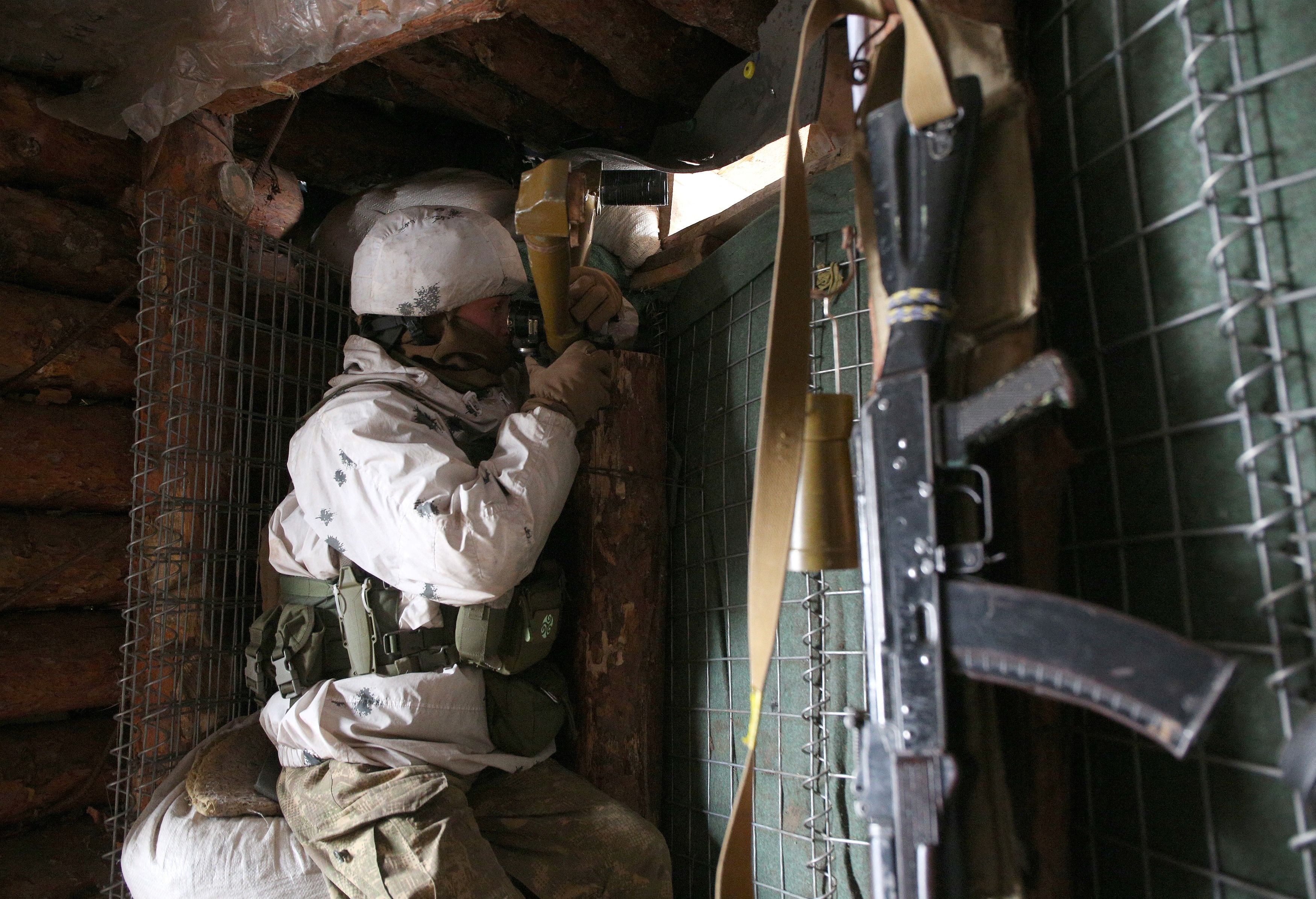 TOPSHOT - An Ukrainian Military Forces serviceman, watches through spyglass in a dugout on the frontline with Russia-backed separatists near Gorlivka, Donetsk region on January 23, 2022. (Photo by Anatolii STEPANOV / AFP) (Photo by ANATOLII STEPANOV/AFP via Getty Images)