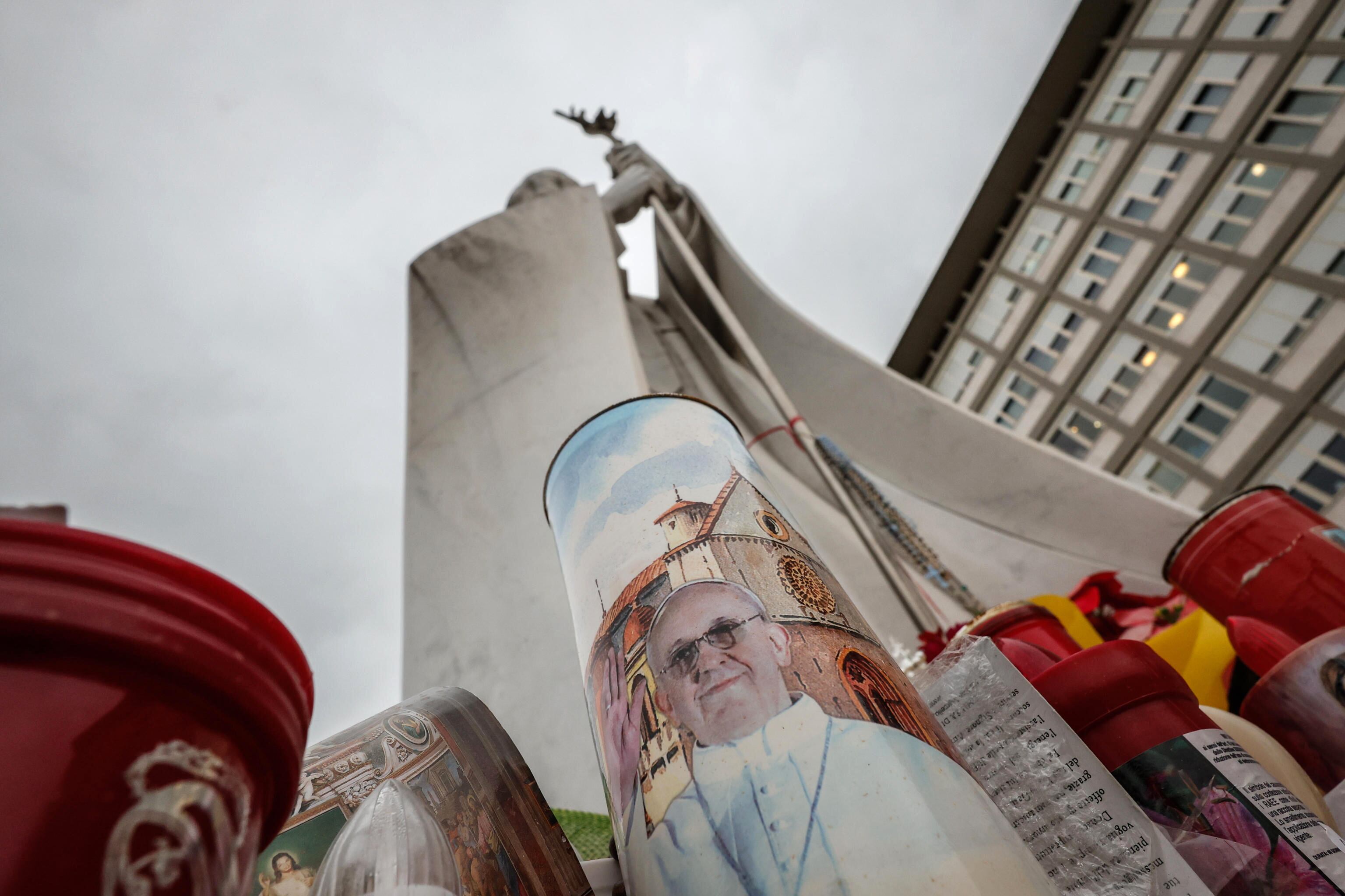 Rome (Italy), 14/03/2025.- Candles with images of Pope Francis at the base of a statue of Pope St. John Paul II outside the Gemelli University Hospital in Rome, Italy, 14 March 2025, where Pope Francis is being treated after he was admitted there on 14 February due to a respiratory tract infection. (Papa, Italia, Roma) EFE/EPA/GIUSEPPE LAMI
