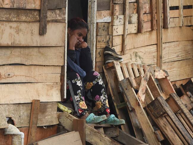 A woman remains sitting at her home of the Moravia neighborhood as local authorities try to implement an eviction order to evacuate families living in alleged illegal constructions, in Medellin, Colombia, on November 3, 2021. - The Moravia neighborhood is known for having been built on a garbage dump and for being from where late drug lord Pablo Escobar set up his first political campaign, and where he helped to build a football field and to install the electric network. (Photo by JOAQUIN SARMIENTO / AFP) (Photo by JOAQUIN SARMIENTO/AFP via Getty Images)