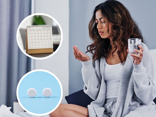 Mujer mirando una pastilla con un vaso de agua y a su lado un calendario y otras pastillas (Getty Images)