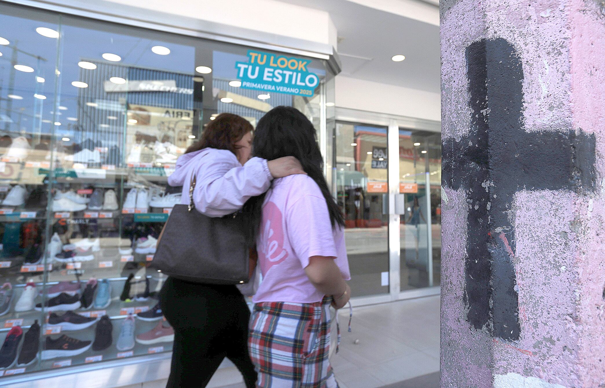 MEX8260. CIUDAD JUÁREZ (MÉXICO), 31/03/2025.- Dos mujeres caminan junto a una cruz que representa personas desaparecidas este domingo, en una calle de Ciudad Juárez, Chihuahua (México). Organizaciones mexicanas que defienden mujeres y niños alertan del aumento de casos de trata de personas y pornografía infantil en Ciudad Juárez después de que la Comisión Estatal de los Derechos Humanos (CEDH) reportó que en esta urbe fronteriza criminales están presuntamente vendiendo niñas. EFE/ Luis Torres