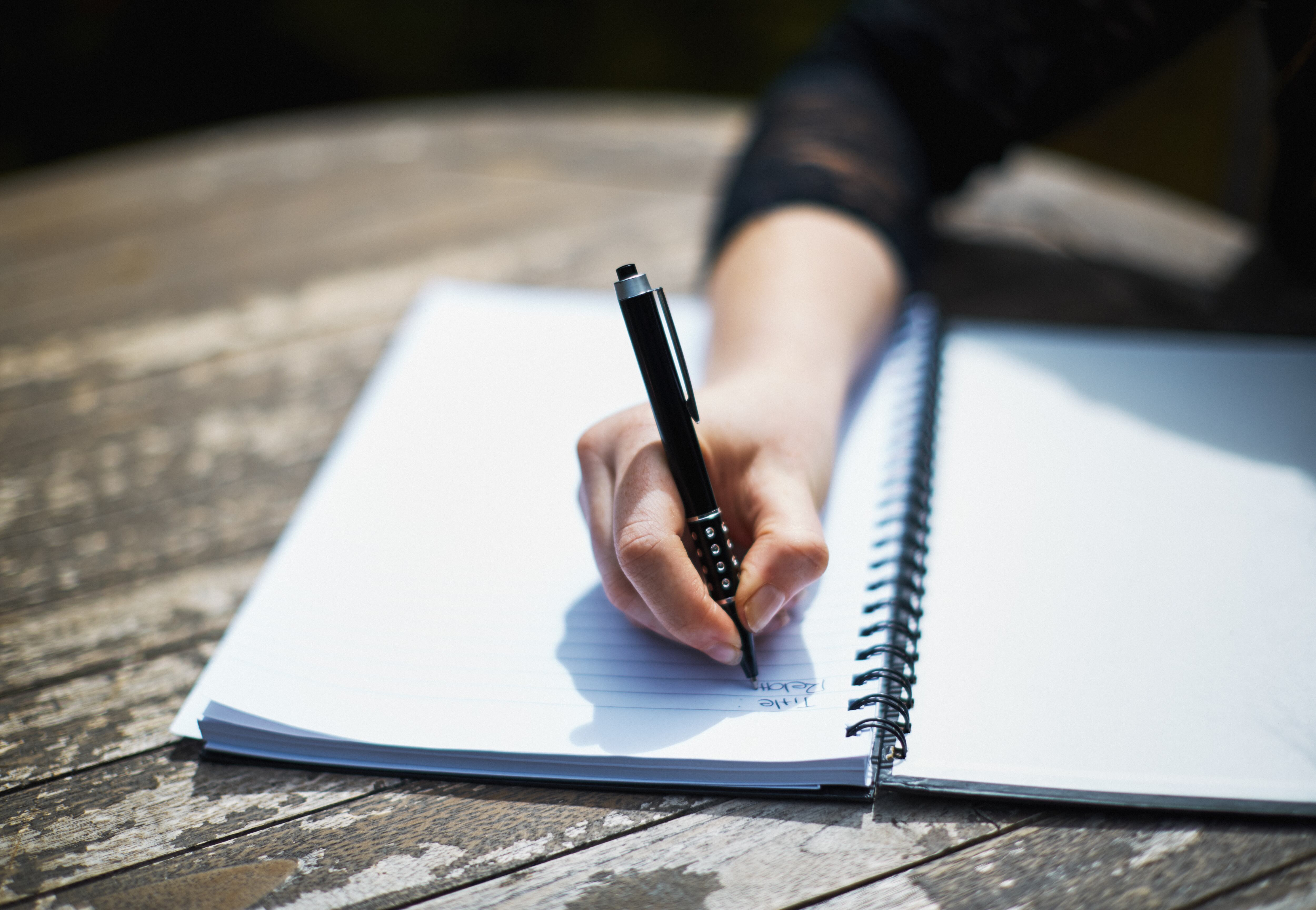 Mujer escribiendo en un cuaderno con un esfero o lapicero de tinta negra / Foto: GettyImages