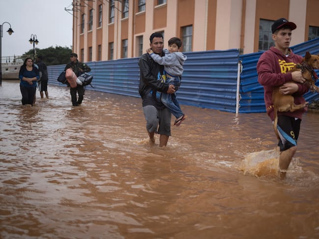 Habitantes de las islas costeras del lago Guaíba caminan entre el agua tras ser rescatados por el ejército brasileño luego de una crecida del río debido a las fuertes lluvia. 
EFE/ Isaac Fontana