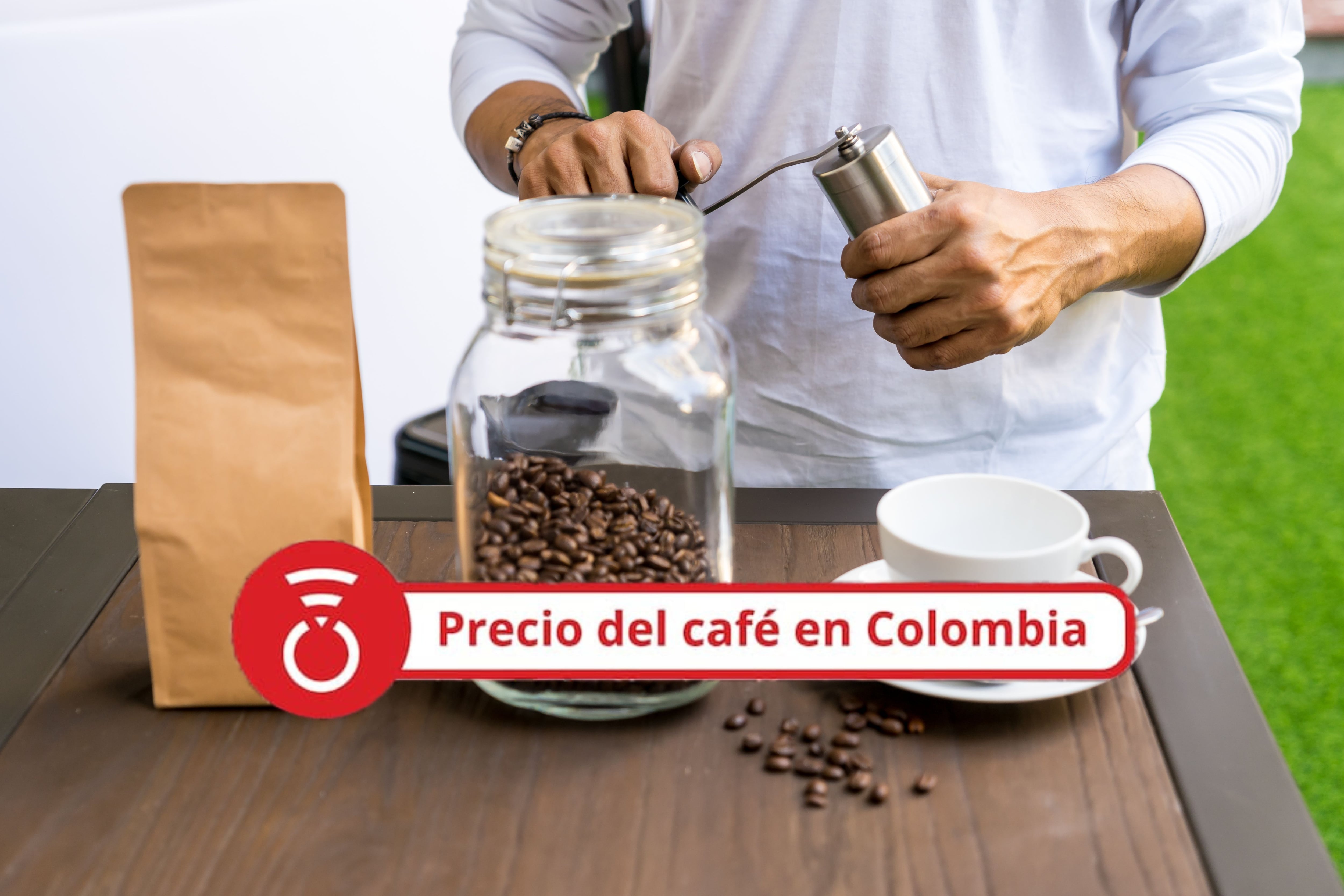 Persona moliendo café con molinillo de café manual al lado del desenfoque de la bolsa de papel marrón en blanco en primer plano. Foto Getty Images