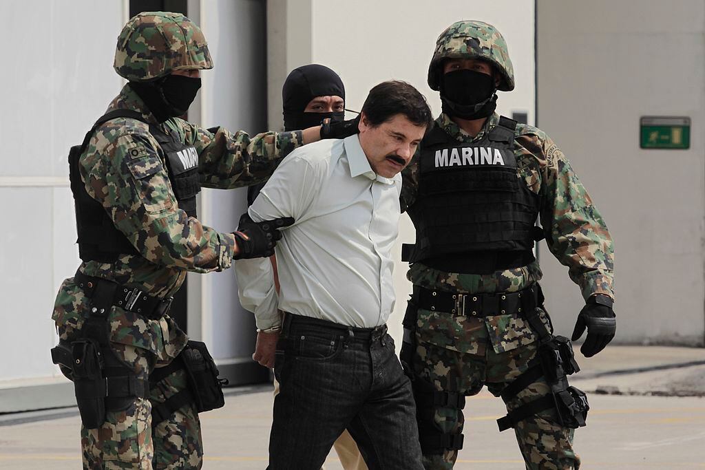 MEXICO CITY, MEXICO - FEBRUARY 22:  Joaquin "El Chapo" Guzman is escorted to a helicopter in handcuffs by Mexican navy marines at a navy hanger. Guzman leader of Mexico's Sinaloa drug Cartel, was captured alive overnight in the beach resort town of Mazatlan, considered the Mexican most-wanted drug dealer on February 22, 2014 in Mexico City, Mexico. (Photo by STR/LatinContent via Getty Images)