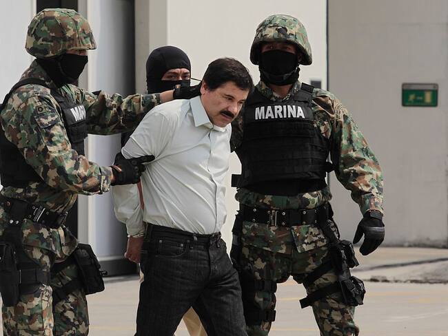 MEXICO CITY, MEXICO - FEBRUARY 22: Joaquin "El Chapo" Guzman is escorted to a helicopter in handcuffs by Mexican navy marines at a navy hanger. Guzman leader of Mexico's Sinaloa drug Cartel, was captured alive overnight in the beach resort town of Mazatlan, considered the Mexican most-wanted drug dealer on February 22, 2014 in Mexico City, Mexico. (Photo by STR/LatinContent via Getty Images)