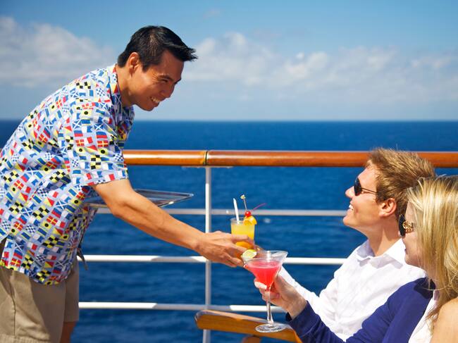 Pareja recibiendo cocteles en un crucero de uno de los trabajadores de la embarcación (Getty Images)