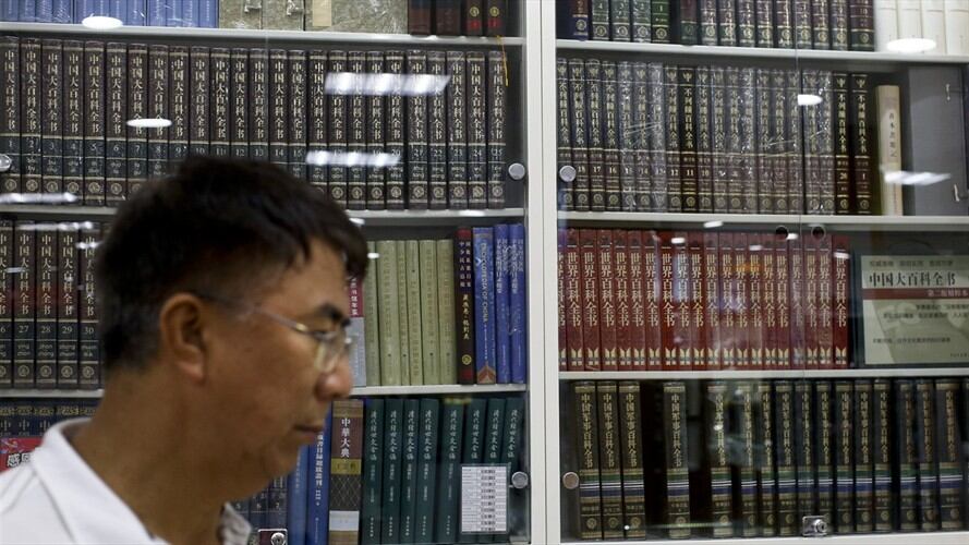 Un hombre pasa frente al escaparate de una librería en Beijing que exhibe enciclopedias, jueves 4 de mayo de 2017. . Foto: Associated Press - AP
