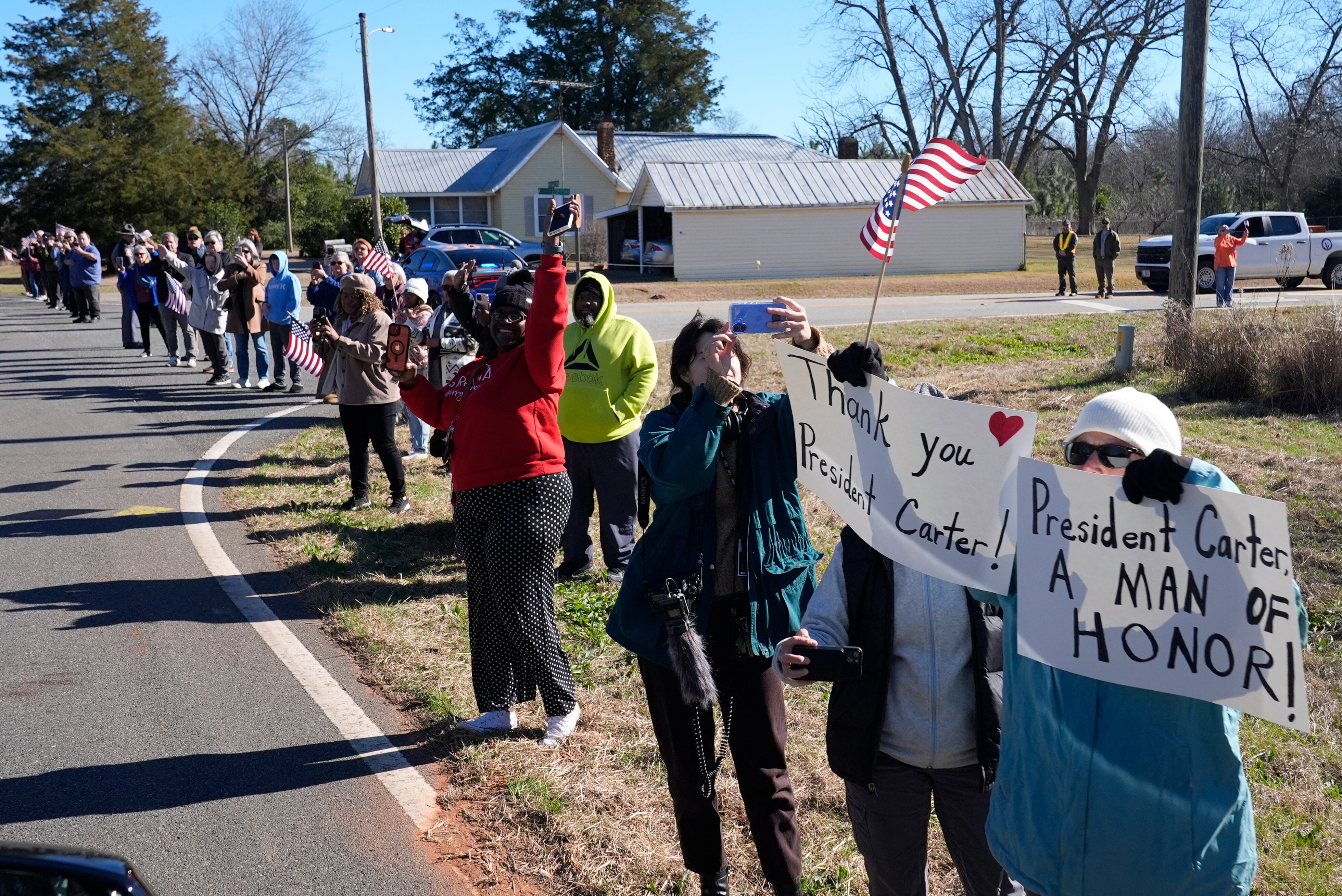 Archery (Usa), 04/01/2025.- People watch as the hearse containing the flag-draped casket of former US President Jimmy Carter departs the Jimmy Carter Boyhood Farm in Archery, as part of his funeral ceremony in Archery, Georgia, USA, 04 January 2025. Carter, who was the oldest-lived former US president, died at age 100 in his hometown of Plains, Georgia, surrounded by his family 29 December 2024. EFE/EPA/ALEX BRANDON / POOL