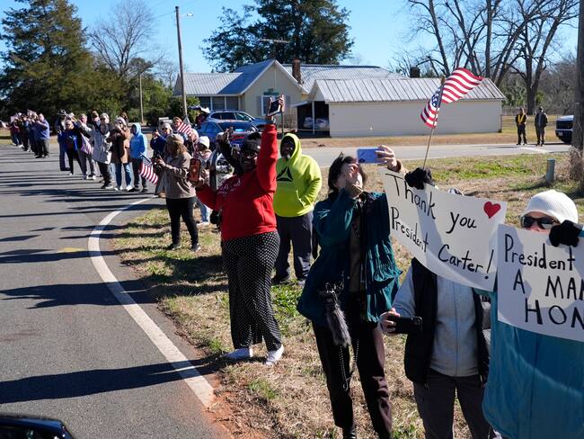 Archery (Usa), 04/01/2025.- People watch as the hearse containing the flag-draped casket of former US President Jimmy Carter departs the Jimmy Carter Boyhood Farm in Archery, as part of his funeral ceremony in Archery, Georgia, USA, 04 January 2025. Carter, who was the oldest-lived former US president, died at age 100 in his hometown of Plains, Georgia, surrounded by his family 29 December 2024. EFE/EPA/ALEX BRANDON / POOL