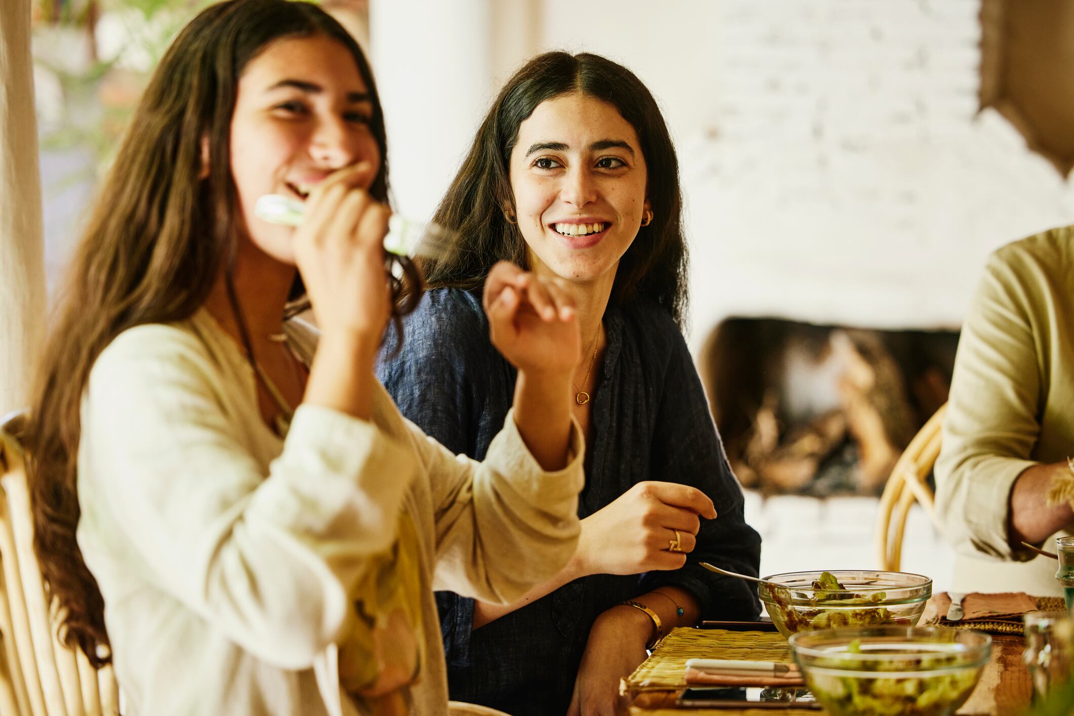 Dos hermanas sonriendo mientras están cenando (Foto vía Getty Images)