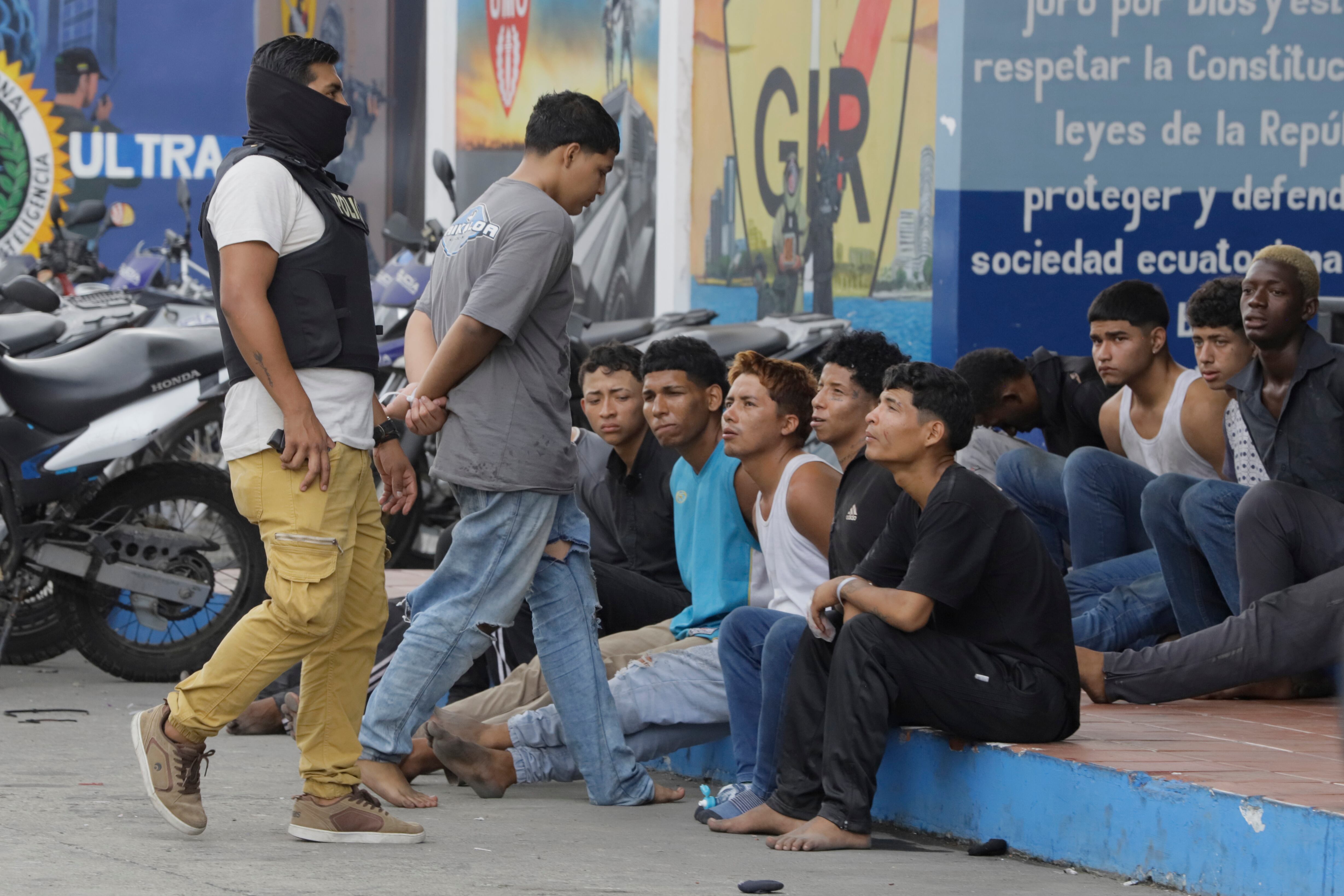 AME8394. GUAYAQUIL (ECUADOR), 10/01/2024.- Un policía custodia hoy a los detenidos de un grupo armado por la toma temporal de un canal de televisión ayer, en Guayaquil (Ecuador). La Policía ecuatoriana confirmó que se detuvieron a trece hombres a los que se les incautaron armas, granadas y material explosivo, luego de que un comando fuertemente armado ocupara durante unas horas un canal de televisión en Guayaquil. Ecuador está en estado de excepción por sesenta días, que incluye un toque de queda durante la noche y madrugada, debido a una serie de incidentes en cárceles, que se desataron el lunes, y la "presunta evasión" de uno de los delincuentes más peligrosos del país. EFE/ Carlos Durán Araújo