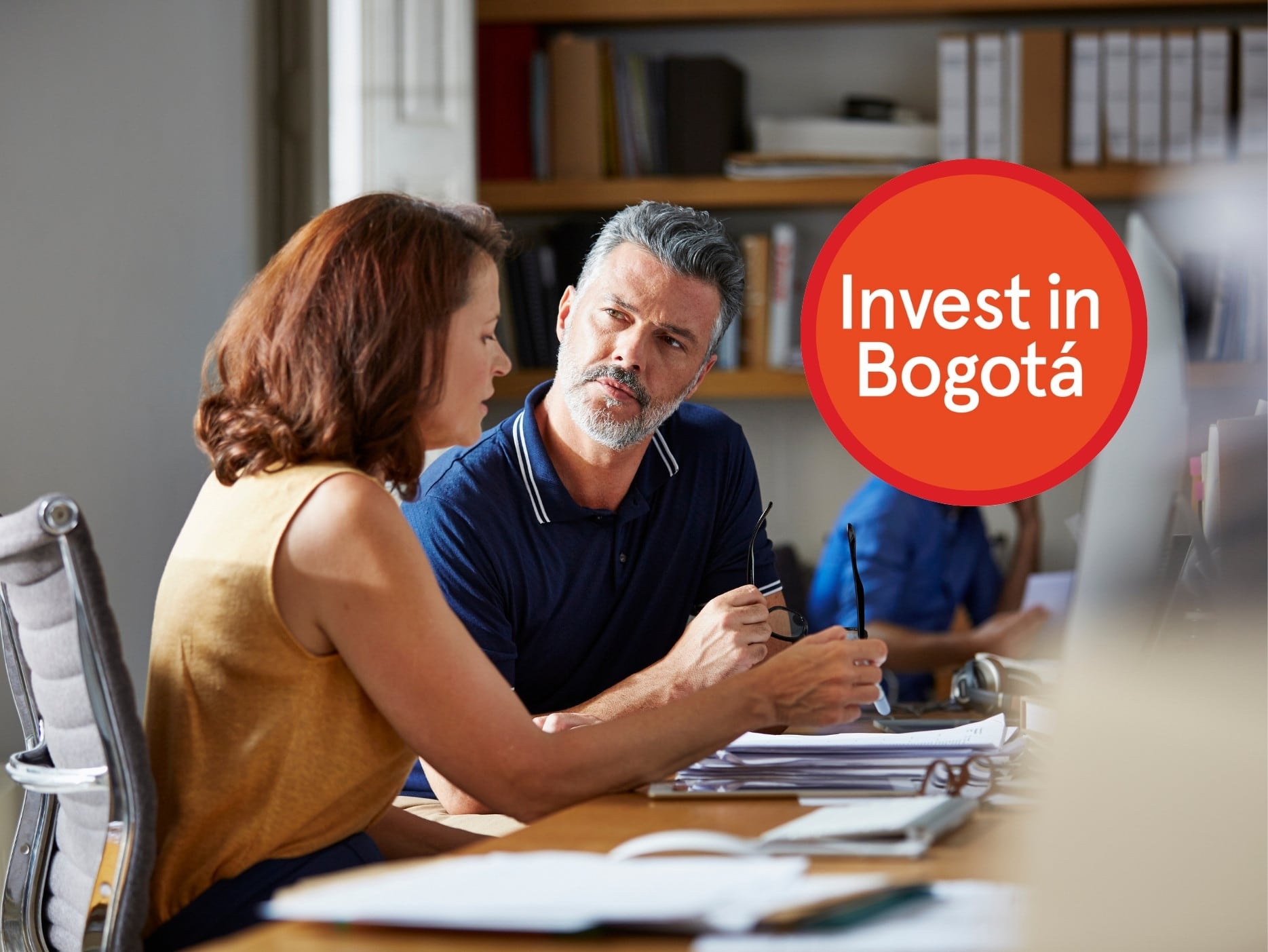 Dos emprendedores charlando. A la derecha, el logo de Invest In Bogotá (Crédito: Getty Images)
