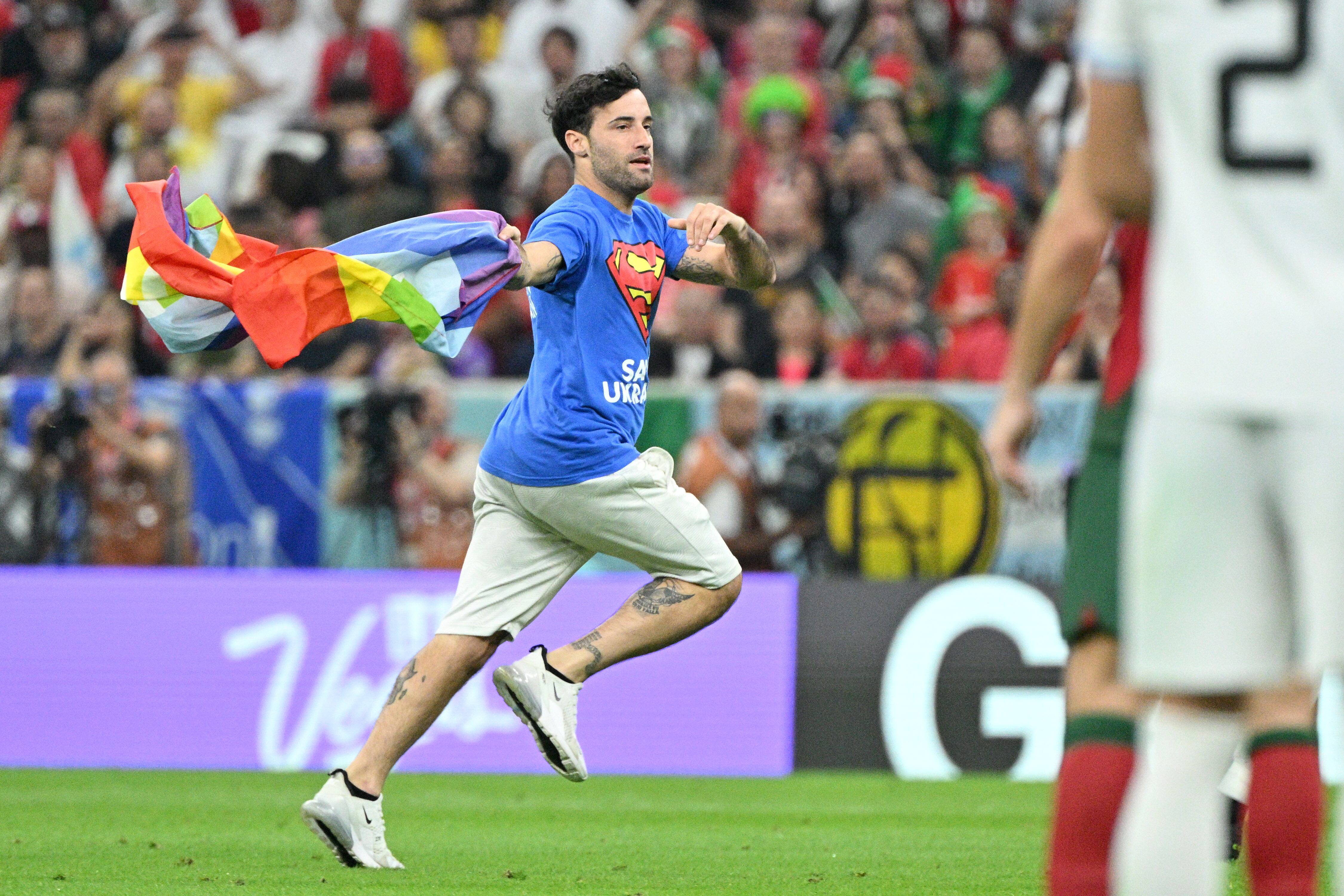 LUSAIL, QATAR - NOVEMBER 28: A fan runs on pitch with rainbow flag during the FIFA World Cup Qatar 2022 match between Portugal v Uruguay at the Lusail Stadium on November 28, 2022 in Lusail Qatar (Photo by Lionel Hahn/Getty Images)