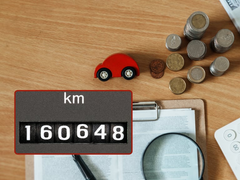 Kilometraje de carro usado / Papeles de un vehículo en venta y una figura de carro (Getty Images)