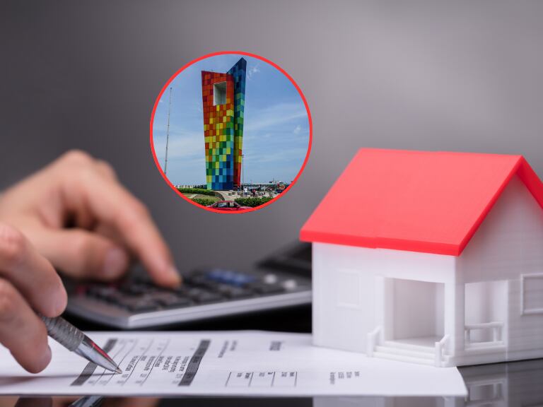 Persona haciendo cuentas sobre el pago de su impuesto predial y de fondo el Monumento Ventana al Mundo ubicado en de Barranquilla (Fotos vía Getty Images)