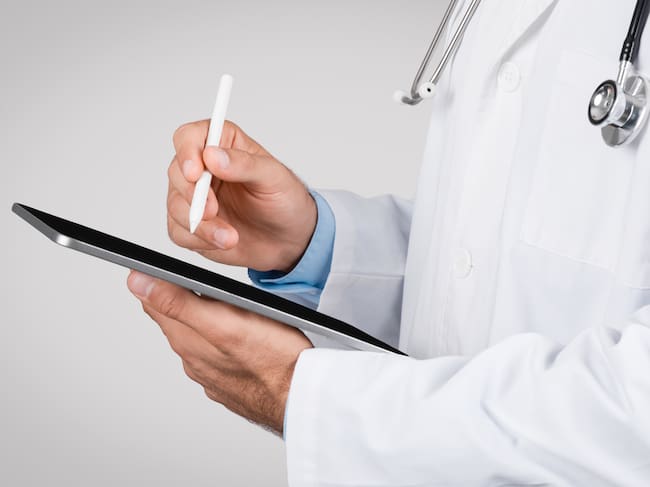 Close-up of medical professional using a stylus pen on a digital tablet, symbolizing modern digital healthcare documentation and telemedicine