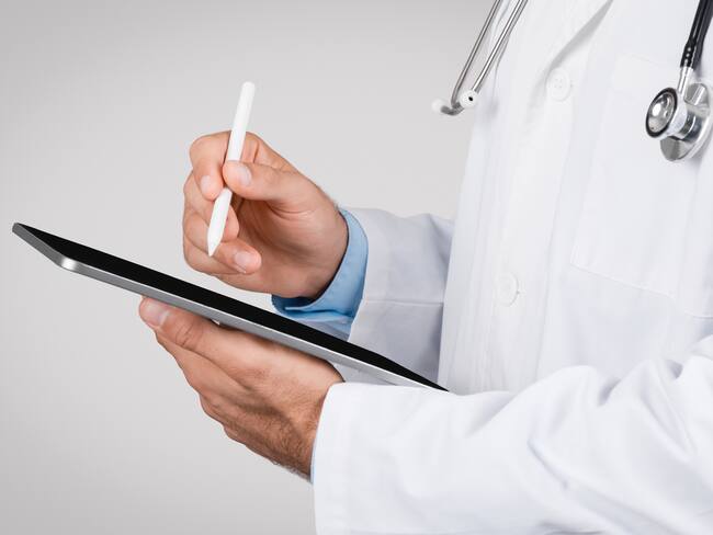 Close-up of medical professional using a stylus pen on a digital tablet, symbolizing modern digital healthcare documentation and telemedicine