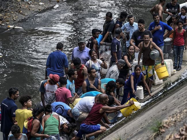 Caraqueños recogen agua en río contaminado debido a la escasez por apagón