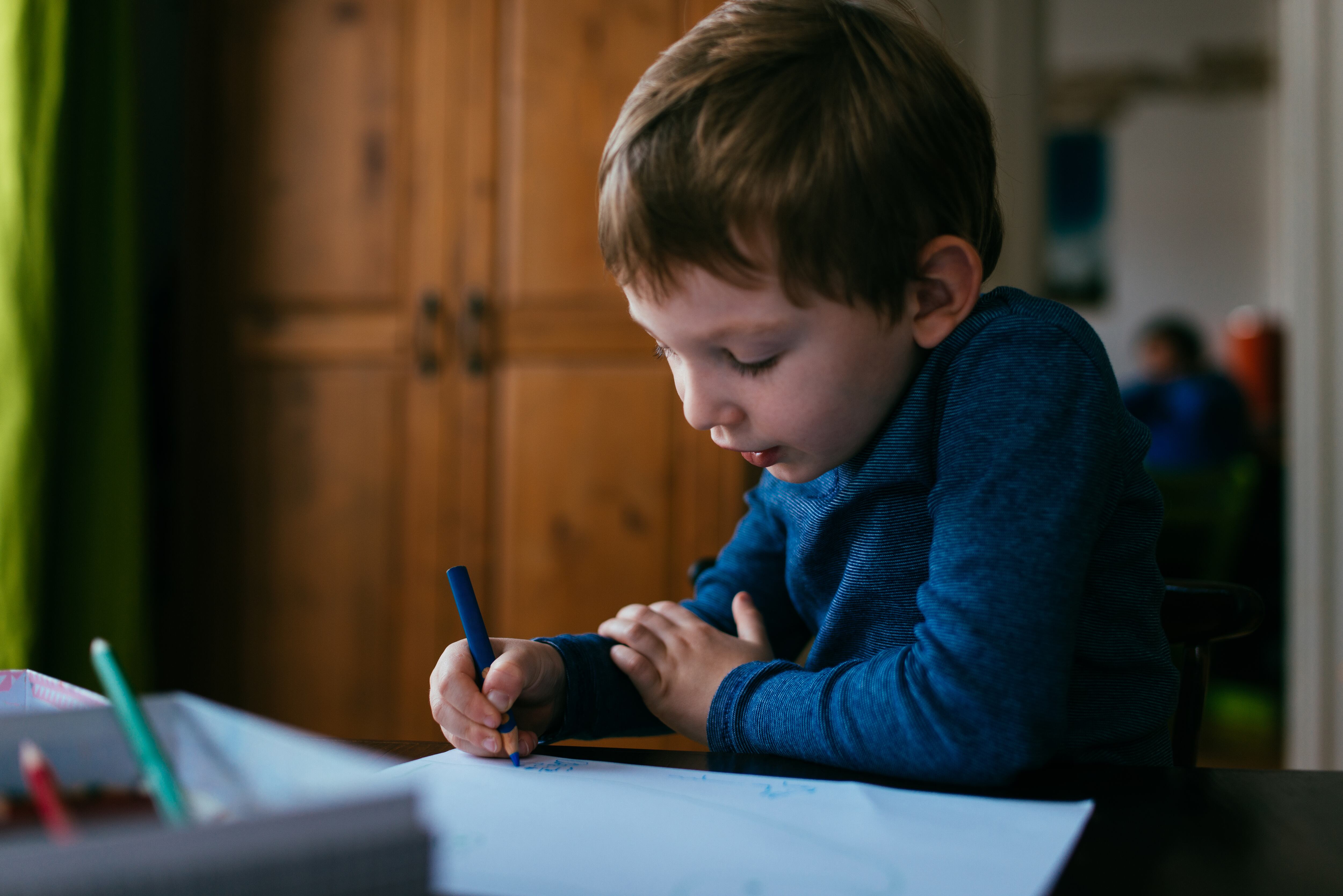Niño dibujando con colores sobre una hoja de papel - Foto vía Getty Images