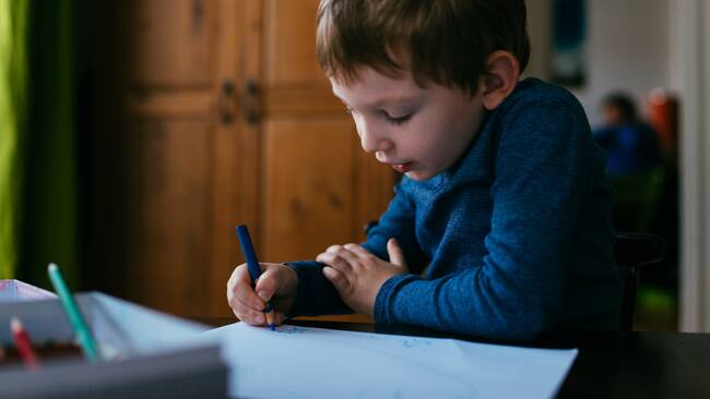 Niño dibujando con colores sobre una hoja de papel - Foto vía Getty Images