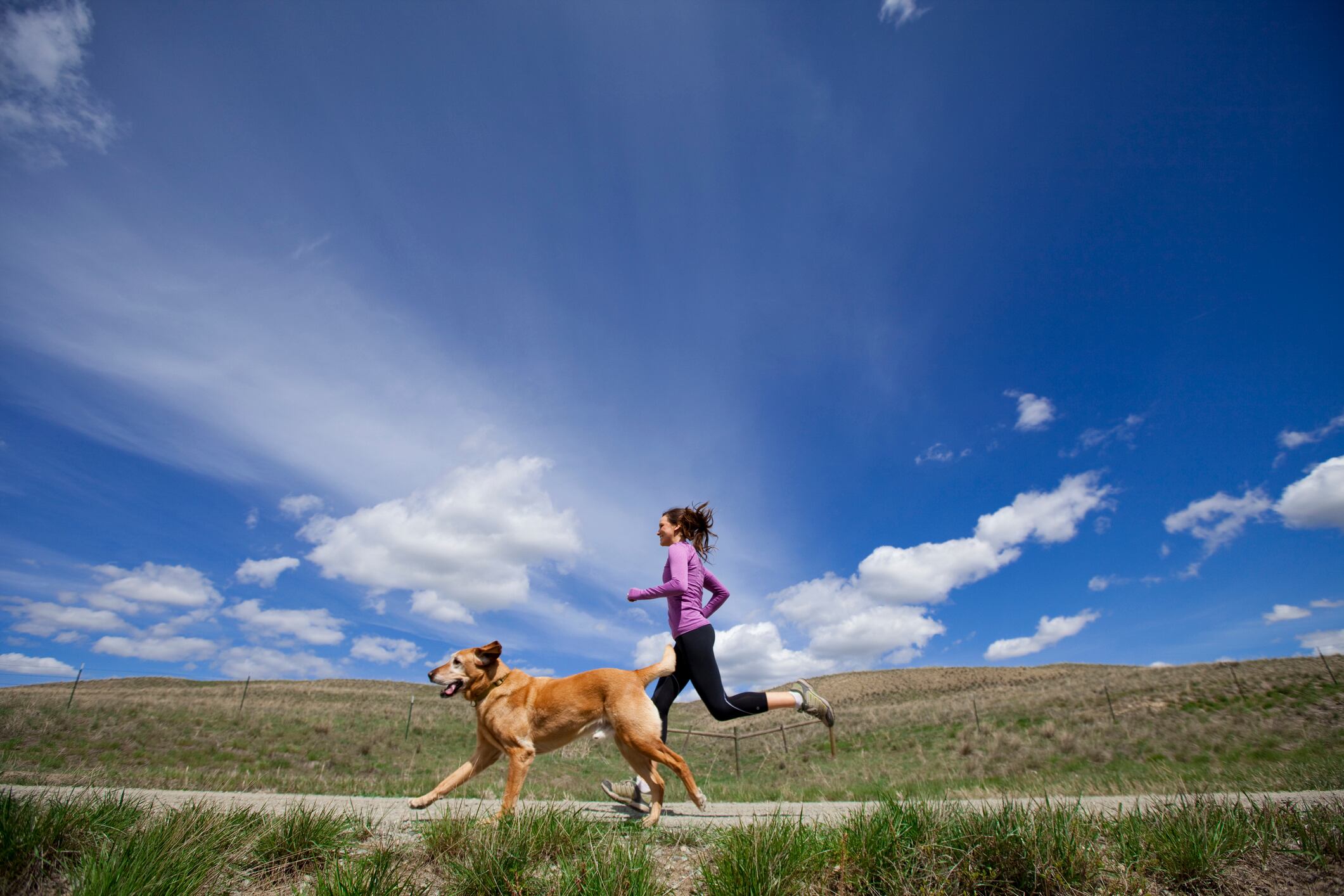 Mujer corriendo junto a un perro // Getty Images