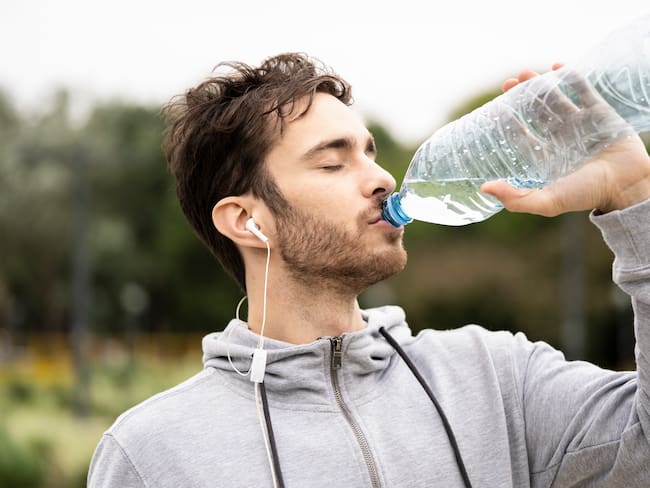 Hombre bebiendo agua de una botella (Foto vía Getty Images)