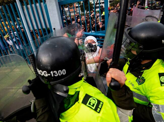 TOPSHOT - An activist argues with riot police during a protest called by feminist groups to denounce an alleged rape of a girl by a doctor in a private clinic and against police brutality in Bogota on September 10, 2020. (Photo by Juan BARRETO / AFP) (Photo by JUAN BARRETO/AFP via Getty Images)