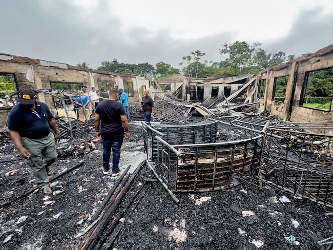 Revisión de las autoridades al dormitorio escolar en Guyana en el que murieron 19 estudiantes por un incendio.
(Foto:    KENO GEORGE/AFP via Getty Images)