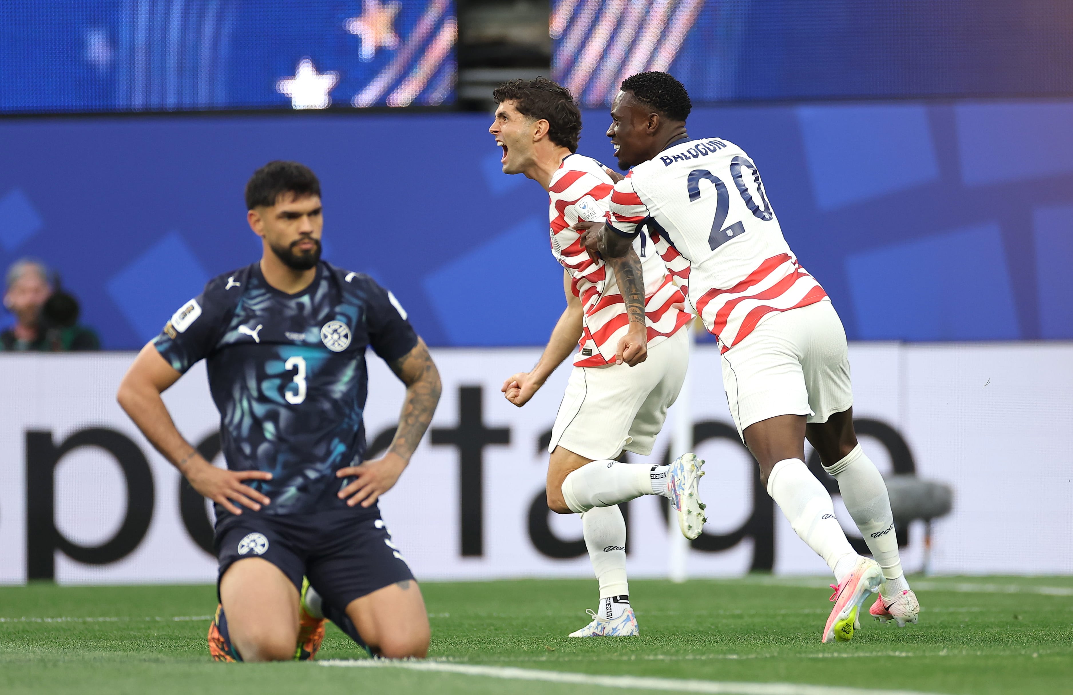 LOS ANGELES, CALIFORNIA - JUNE 12: Christian Pulisic #10 and Folarin Balogun #20 of the United States celebrate their side's first goal, an own goal by Damian Bobadilla #16 of Paraguay (not pictured), during the FIFA World Cup 2026 Group D match between USA and Paraguay at Los Angeles Stadium on June 12, 2026 in Los Angeles, California. (Photo by Sarah Stier - FIFA/FIFA via Getty Images)