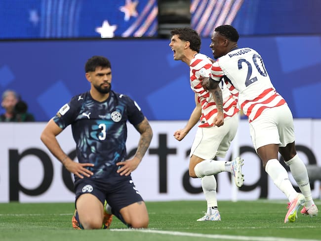 LOS ANGELES, CALIFORNIA - JUNE 12: Christian Pulisic #10 and Folarin Balogun #20 of the United States celebrate their side's first goal, an own goal by Damian Bobadilla #16 of Paraguay (not pictured), during the FIFA World Cup 2026 Group D match between USA and Paraguay at Los Angeles Stadium on June 12, 2026 in Los Angeles, California. (Photo by Sarah Stier - FIFA/FIFA via Getty Images)