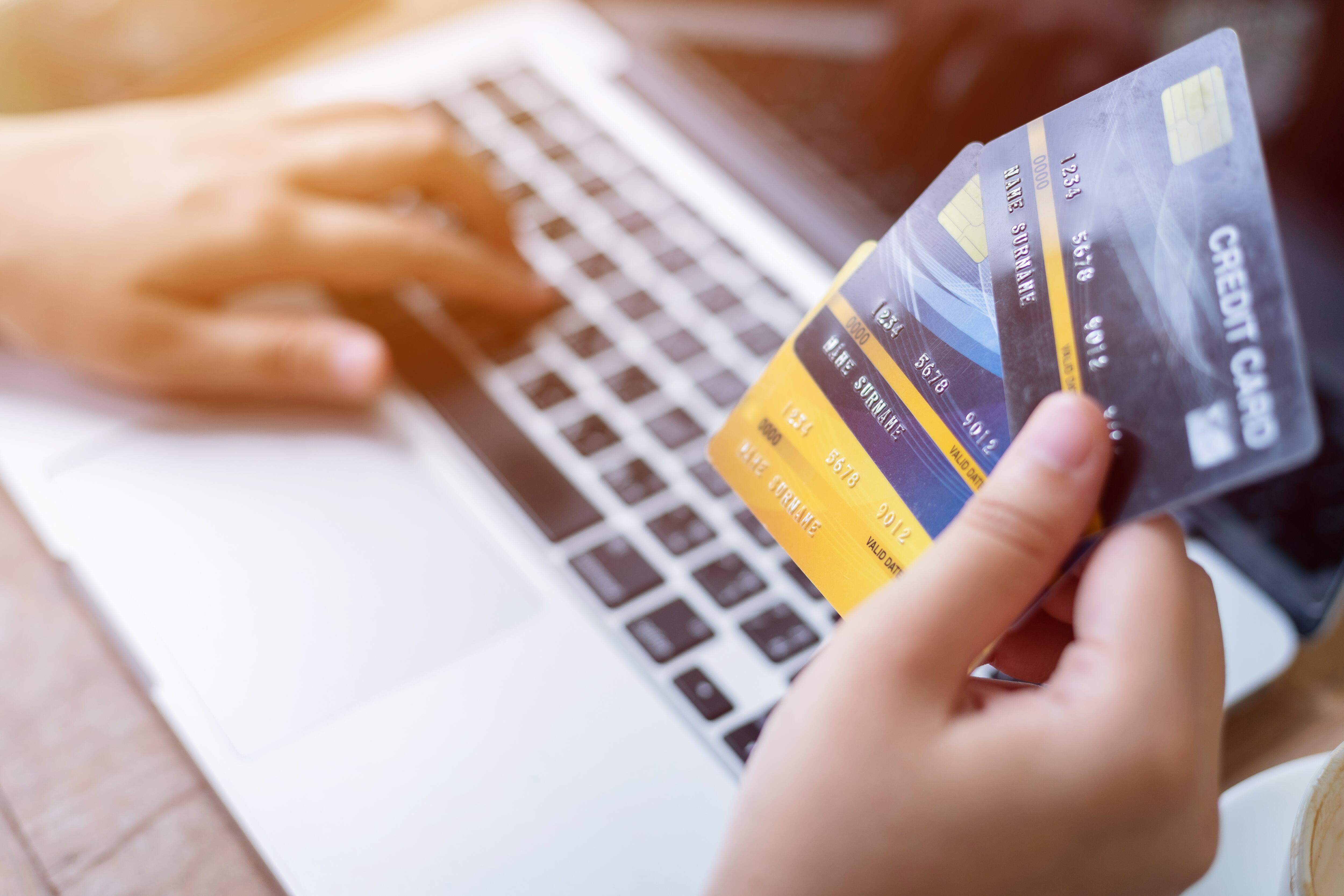 Persona con tres tarjetas de crédito y un computador. (Foto: Getty Images)