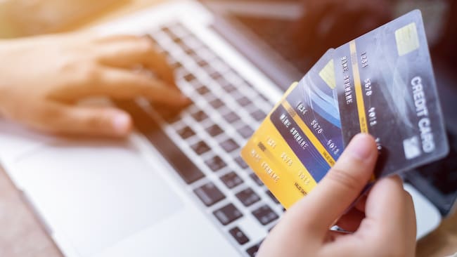 Persona con tres tarjetas de crédito y un computador. (Foto: Getty Images)