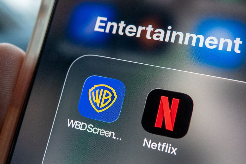 BRISTOL, UNITED KINGDOM - DECEMBER 09: In this photo illustration a man holds a iPhone, that shows Netflix and Warner Bros streaming apps on his phone screen on December 9, 2025 in Bristol, England. Yesterday US production company Paramount said that it was now looking to challenge Netflix's takeover of Warner Bros. Discovery (WBD) with a hostile bid of its own. (Photo by Anna Barclay/Getty Images)