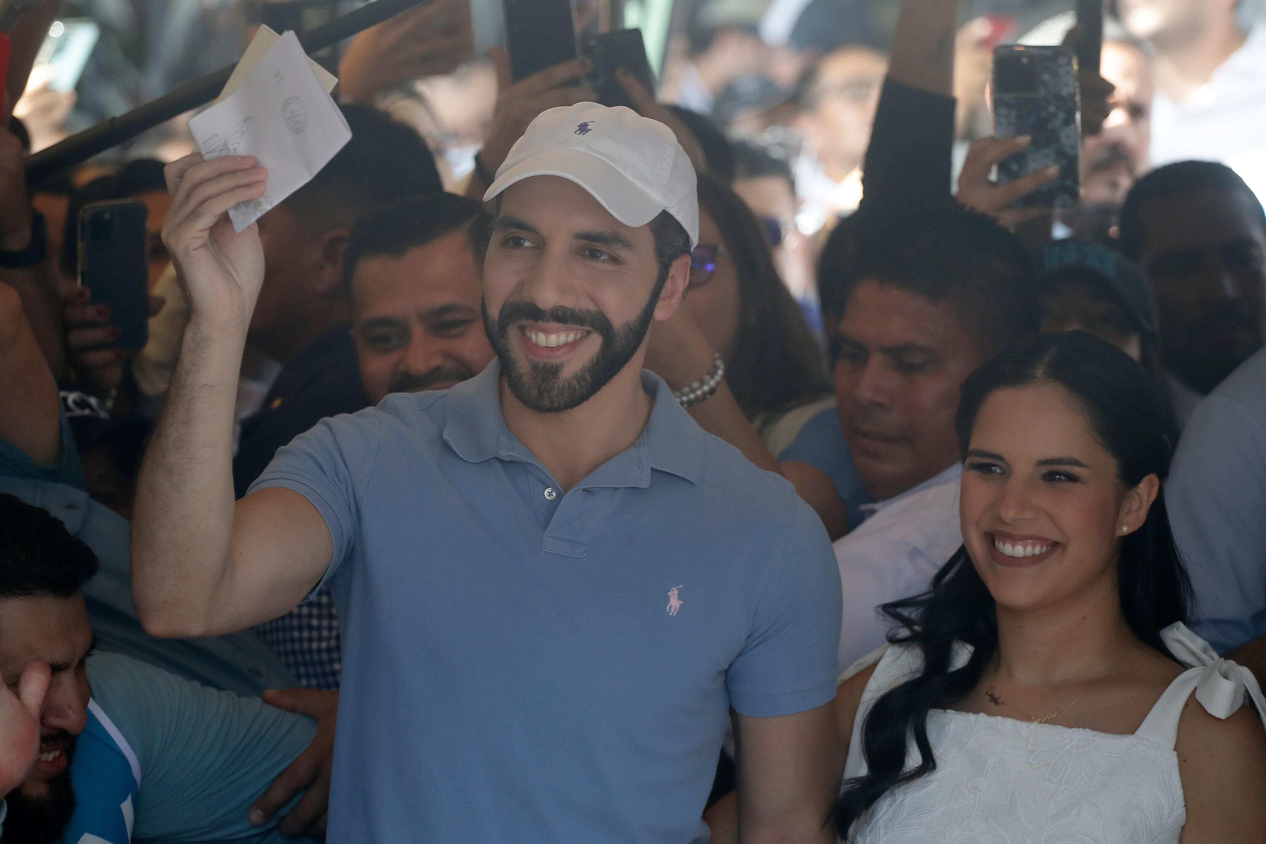 . SAN SALVADOR (EL SALVADOR), 04/02/2024.- El presidente de El Salvador y candidato a la reelección inmediata, Nayib Bukele acompañado de su esposa Gabriela de Bukele, vota hoy en San Salvador (El Salvador). El presidente de El Salvador y candidato a la reelección inmediata, Nayib Bukele, votó este domingo en medio de un fuerte dispositivo de seguridad, rodeado de miembros de su partido Nuevas Ideas (NI), cientos de seguidores y bajo la mirada de un buen grupo fotógrafos y periodistas nacionales y extranjeros. EFE/Rodrigo Sura