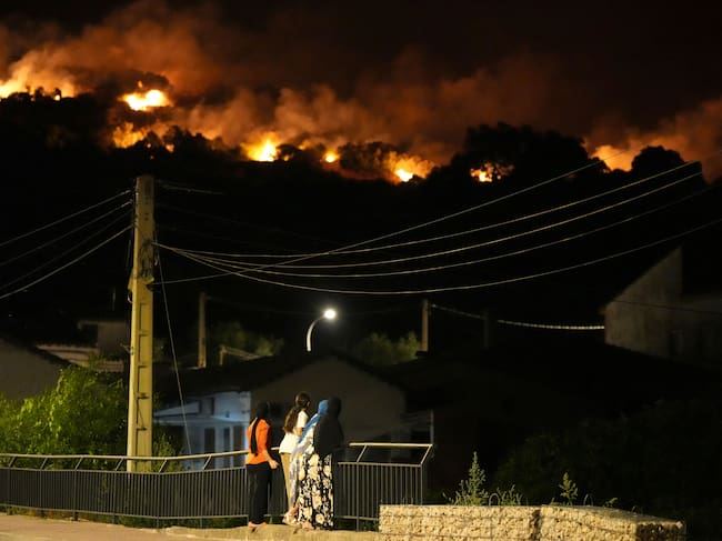 Los residentes observan las llamas en las cimas de las colinas mientras los bomberos combaten un incendio forestal en la zona de Cebreros, cerca de Ávila, a 80 km al oeste de Madrid, la noche del 24 de julio de 2026. Los peores incendios forestales de la historia de la Comunidad de Madrid asolan el oeste de la capital española, obligando a las autoridades a evacuar o a ordenar a unas 40.000 personas que permanezcan en sus casas. (Foto de César Manso / AFP)