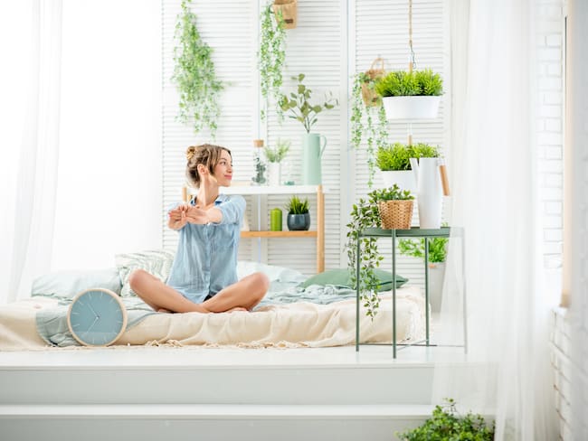 Mujer en un dormitorio con plantas (Foto vía Getty Images)