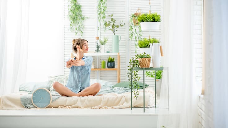 Mujer en un dormitorio con plantas (Foto vía Getty Images)
