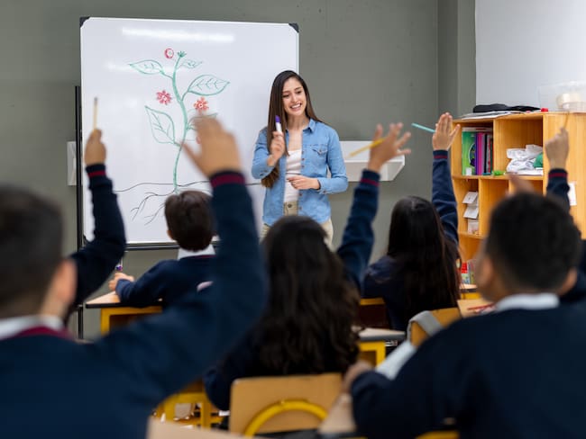 Latin American students raising their hand after the teacher asked a question in class at an elementary school