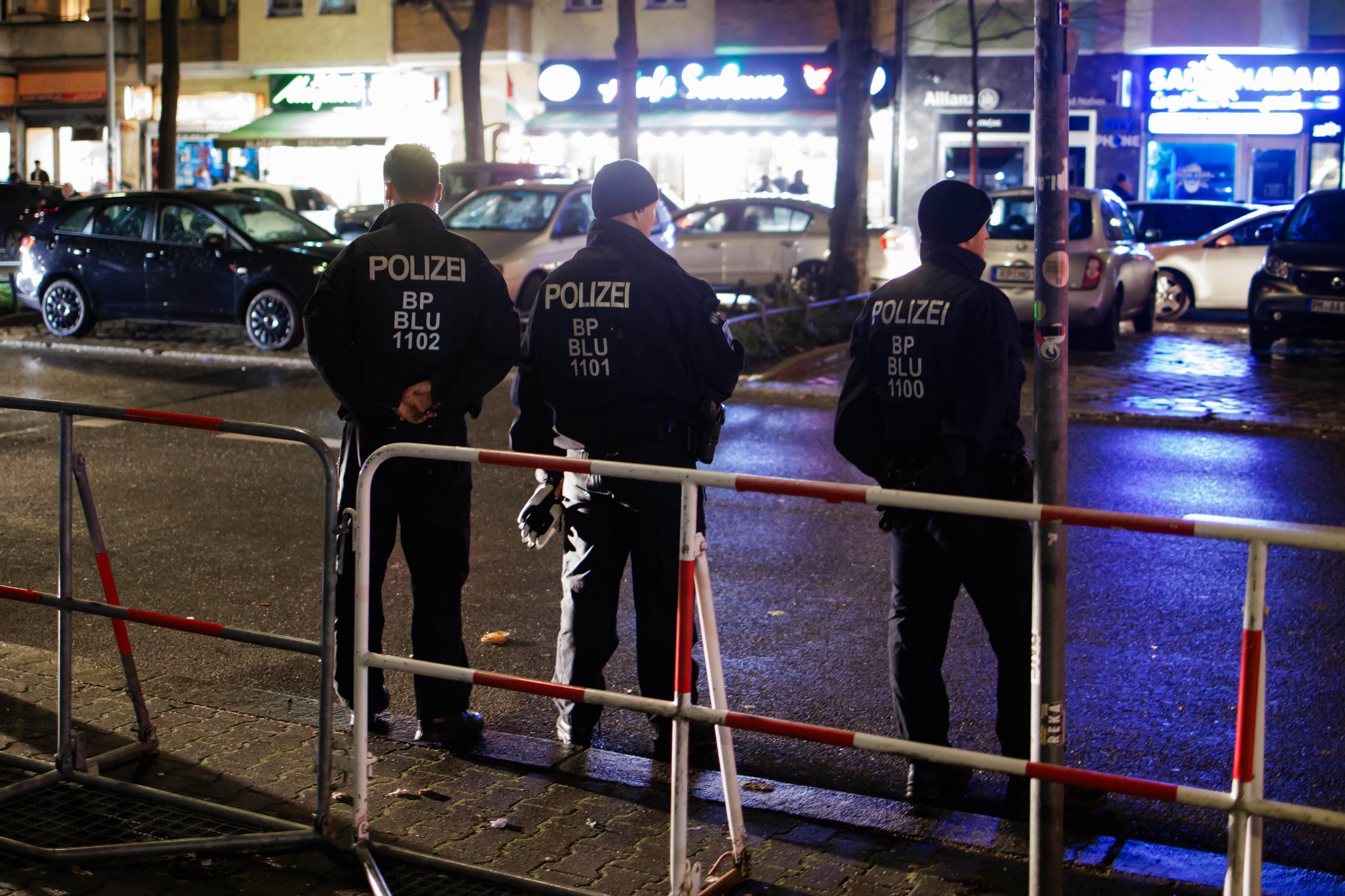 Berlin (Germany), 31/12/2023.- Police officers keep watch behind barriers at Sonnenallee street in the district Neukoelln in Berlin, Germany, 31 December 2023. Three pyrotechnics ban zones have been set up in Berlin. The ban applies from New Year's Eve at 6 pm until New Year's Day at 6 am. (Alemania) EFE/EPA/CLEMENS BILAN