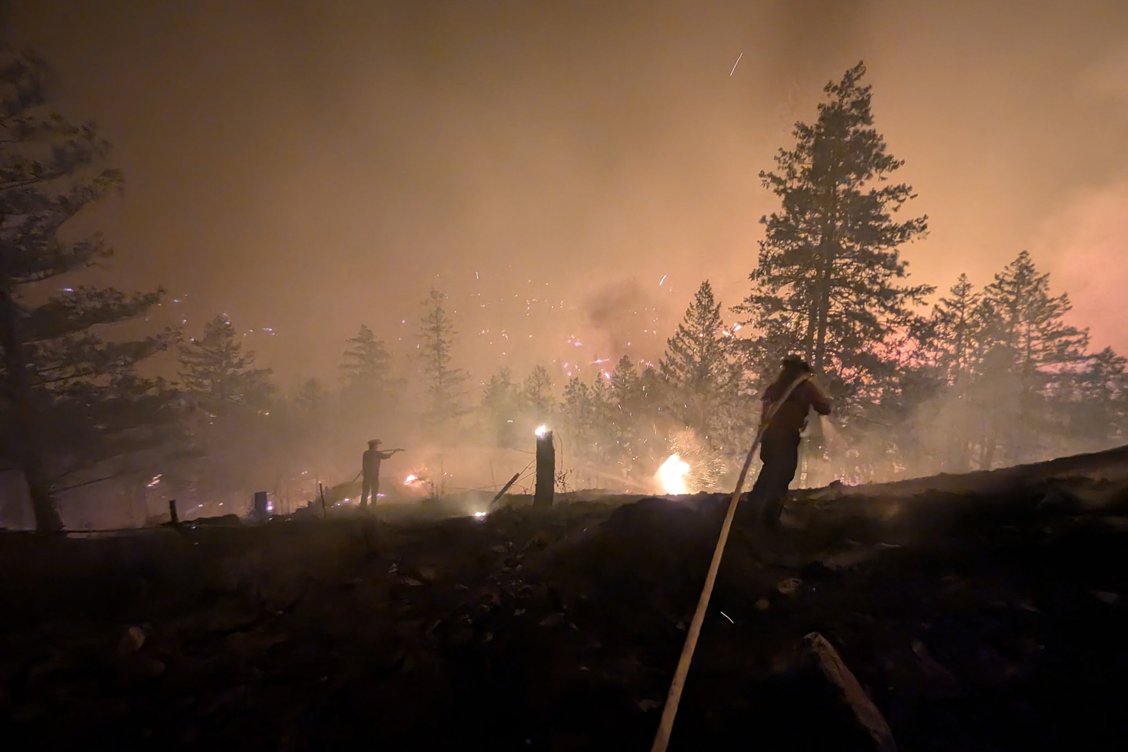 This handout photo taken on August 7, 2026, and released on August 8 by the BC Wildlife Service shows firefighters battling the Bald Range wildfire near Summerland in Canada's western British Columbia province. Canadian officials declared a state of emergency August 8 after a fast-moving wildfire in the western province of British Columbia forced the overnight evacuation of more than 20,000 people, including some who were airlifted to safety. (Photo by Handout / BC Wildfire Service / AFP) / -----EDITORS NOTE --- RESTRICTED TO EDITORIAL USE - MANDATORY CREDIT "AFP PHOTO /  BC Wildfire Service" - NO MARKETING - NO ADVERTISING CAMPAIGNS - DISTRIBUTED AS A SERVICE TO CLIENTS